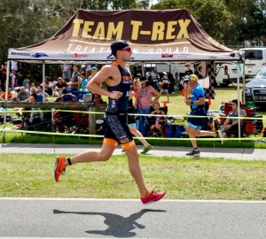 Team T-Rex Member Running with Support Team Behind in a Triathlon